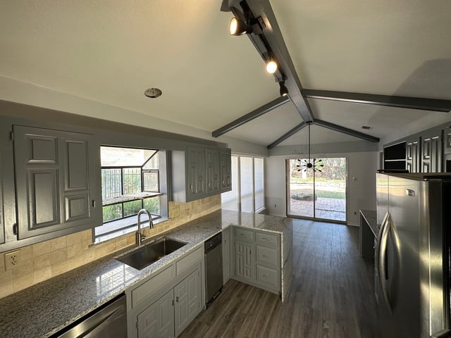 Kitchen with granite countertops, gray cabinets and vaulted beamed ceiling