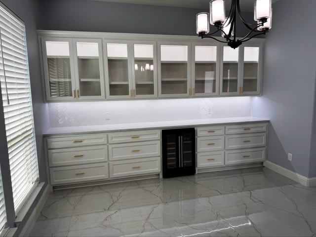 Custom built-in butler pantry cabinetry with wine fridge and marble tile floor