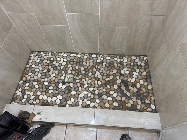 Tiled shower pan with pebble stone floor and center drain