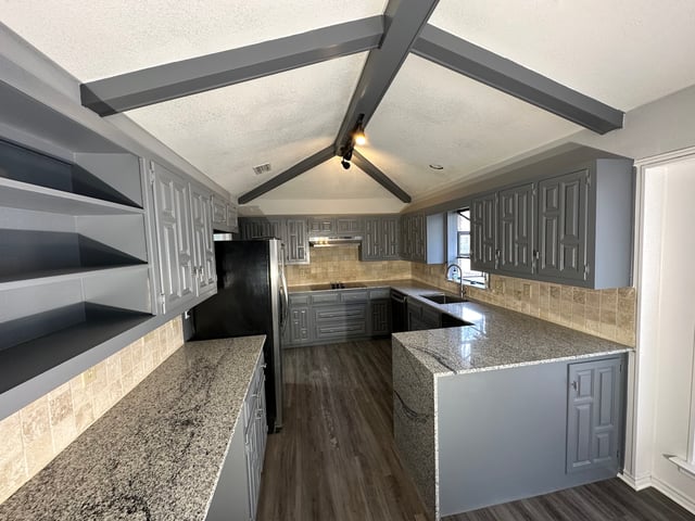Repainted gray kitchen cabinets with granite counters and open shelving