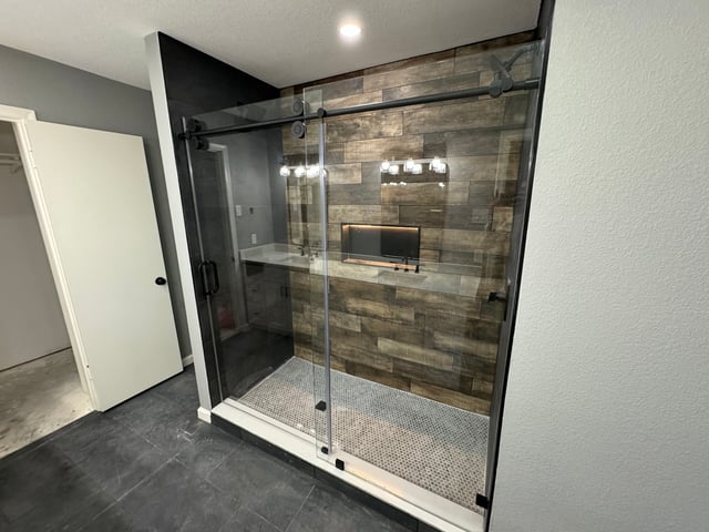 Walk-in shower remodel with sliding glass doors and wood-look tile wall